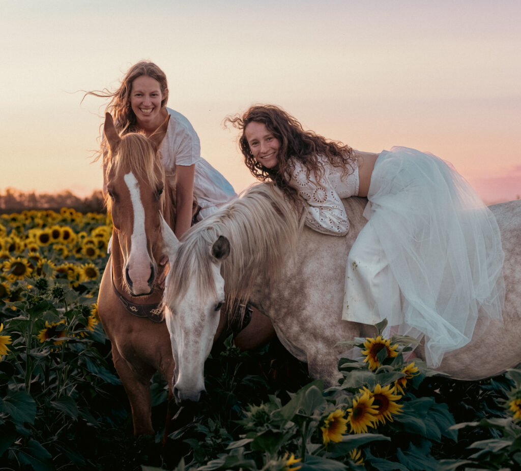 Tanja Riedinger und Bettina Rittler mit ihren Pferden im Sonnenblumenfeld im Abendlicht